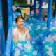 Meitene bumbu baseinā ar caurspīdīgām baltām un zilām bumbām.